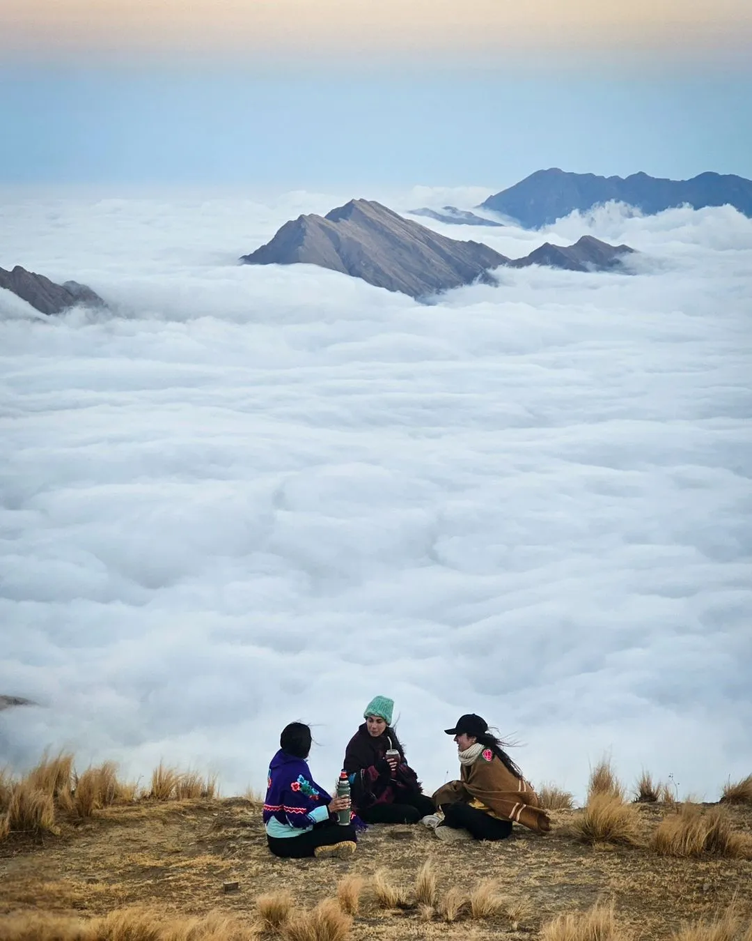 Tres viajeras tomando mate sobre el colchón de nubes al atardecer, cerca de Santa Ana, Jujuy